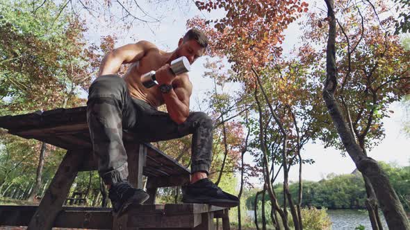 Man doing exercise with dumbbell. Portrait of man exercising with dumbbell in park