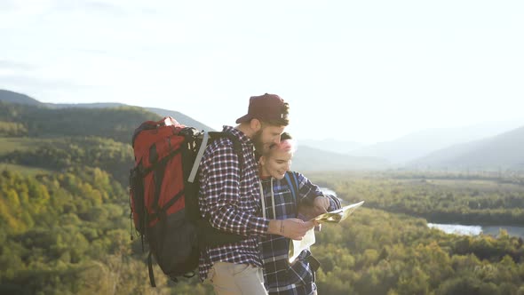 Portrait Shot of Young Man and Woman with Map in the Mountains