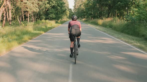 Female cyclist cycling on countryside road. Woman athlete training on bicycle