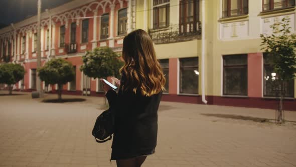 A Spectacular Young Girl Goes in the Evening Through the Historic Quarter of the City and Leafs