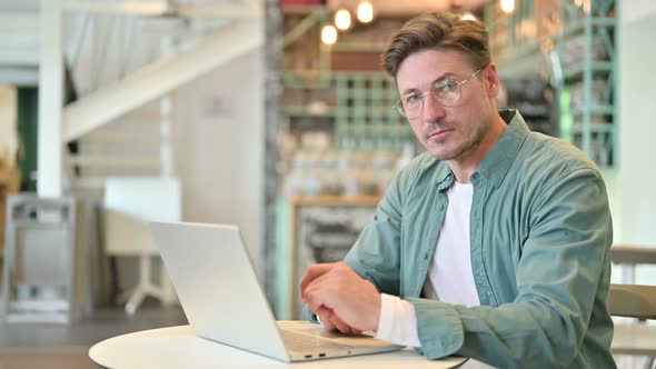 Serious Middle Aged Man with Laptop Saying No with Finger Sign