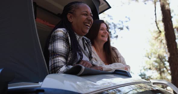 Senior women friends having fun traveling around the mountains with camper van