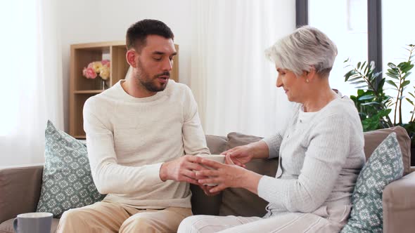 Adult Son and Senior Mother Drink Coffee at Home