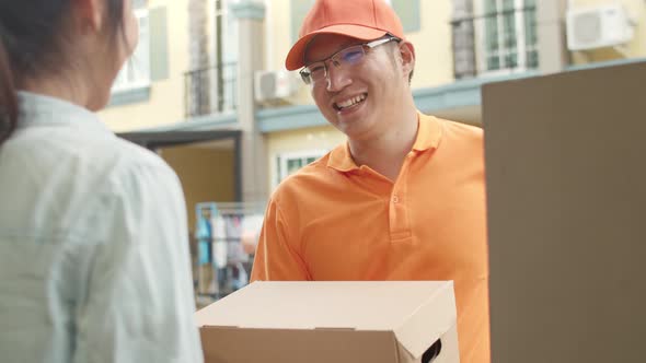 Asian women signing and pay via qr code on mobile phone for receive delivered parcels outdoors.