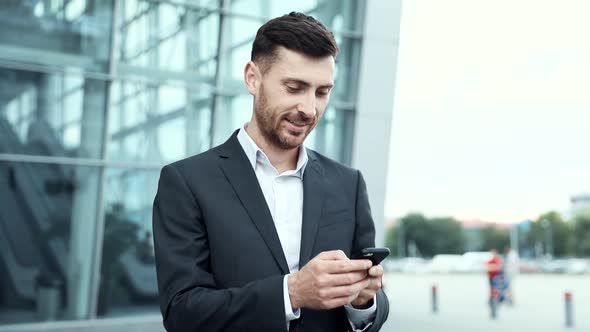 Young Handsome Man Wearing Elegant Suit. Checking Mails on his Smartphone