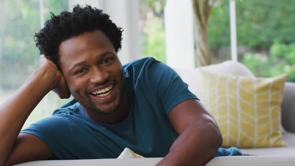 Portrait of biracial man sitting on sofa and smiling to camera