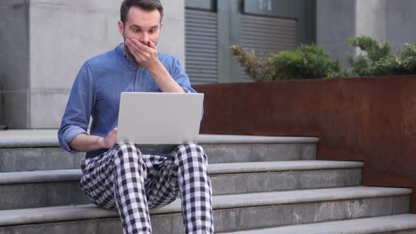 Shocked Stunned Casual Man Using Laptop While Sitting on Stairs Outside Office