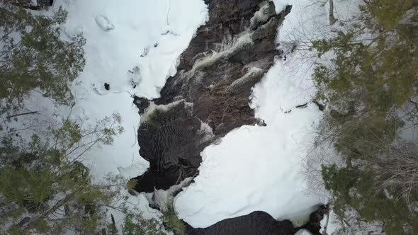 Top down drone shot of snowy river rapids in winter