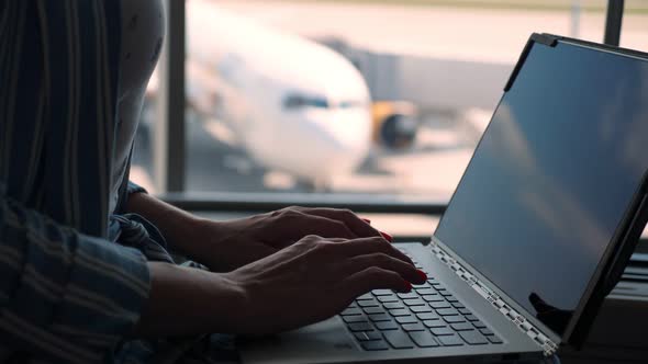 Close-up, Female Hands Are Typing on a Laptop Against Panoramic Window Background. with Passenger