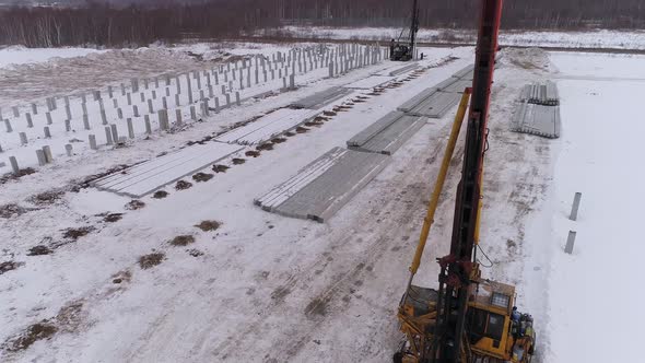 Aerial drone view of a pile bore machines at winter construction site 06