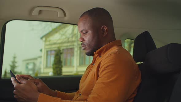 Black Man in Car Backseat Networking on Tablet Pc