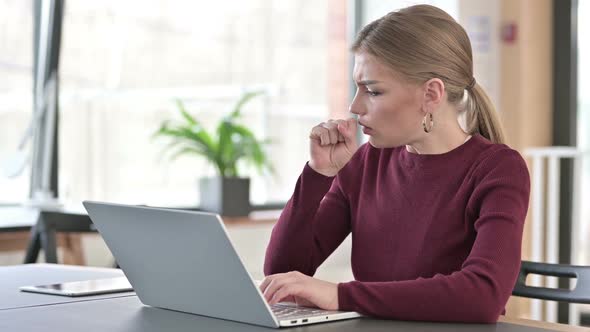 Young Woman Using Laptop Coughing in Office