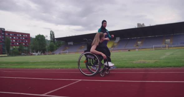 A Female Person with Disabilities Riding a Wheelchair on a Athletics Training Track with Muslim