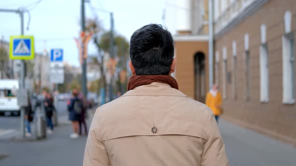 A Man in a Coat is Walking Down the Street