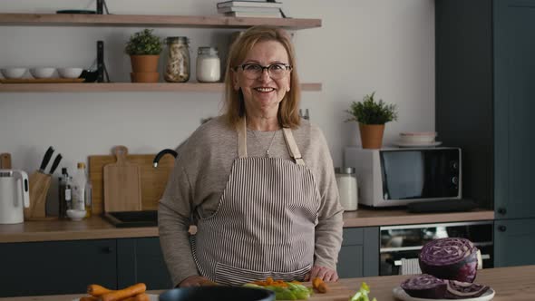 Portrait of caucasian senior woman standing in the kitchen and smiling.