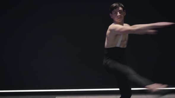 Camera Moving Up From Feet of Ballet Dancer To Face of Confident Man Spinning in Darkness