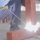 A man in a blue working uniform, in leather brown gloves, performs welding work - VideoHive Item for Sale