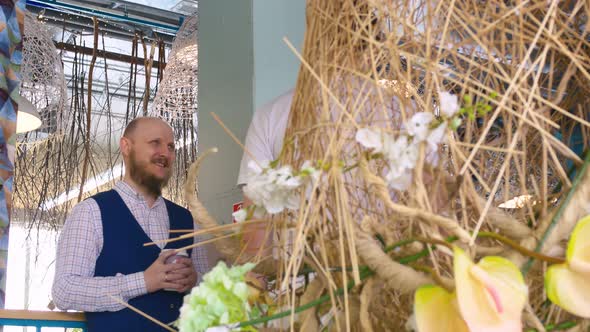 Two Friends are Talking and Smiling a Bald Man with a Beard Holding a Mug of Coffee in His Hands