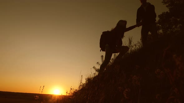 Adventure and Travel Concept. Tourists Descend From Mountain at Sunset, Holding Hands. Male Traveler