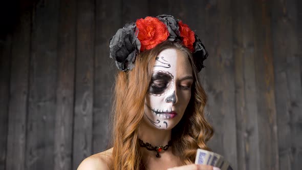 Lady Model with Skull Makeup Shows Cards Against Wooden Wall