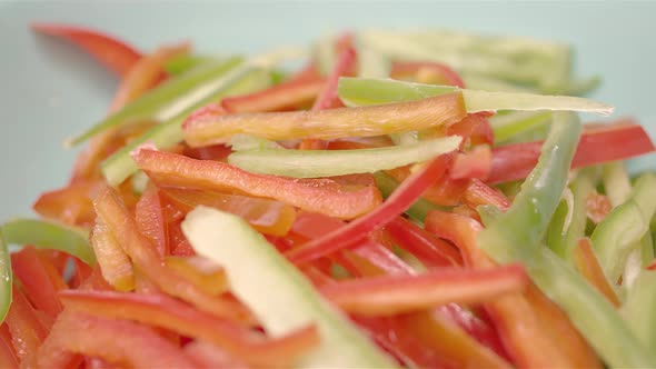 Green and red sliced peppers in a bowl