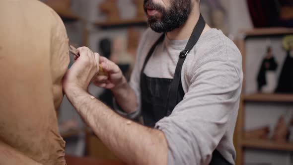 Focused craftsman shaping wooden detail with chisel