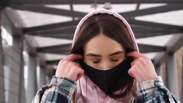 A young attractive girl removes her protective mask to breathe fresh air. Symbol of pandemic, epidem