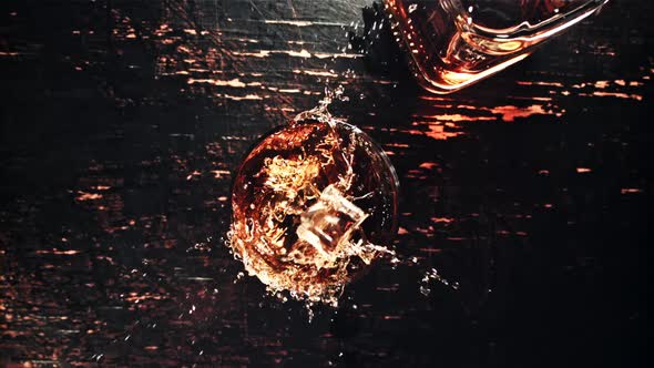 Ice Cubes with Splashes Fall Into a Glass of Whiskey