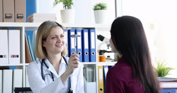 Female Neurologist Checking Visual Reflexes of Nervous System Using Hammer in Clinic