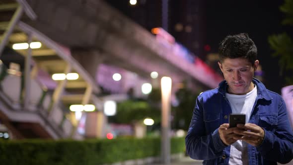 Hispanic Man Using Phone While Exploring the City Streets at Night