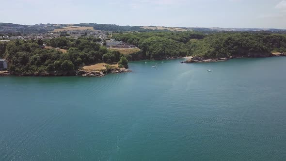 Flying towards Brixham beach in England. Boats docked off the shore.