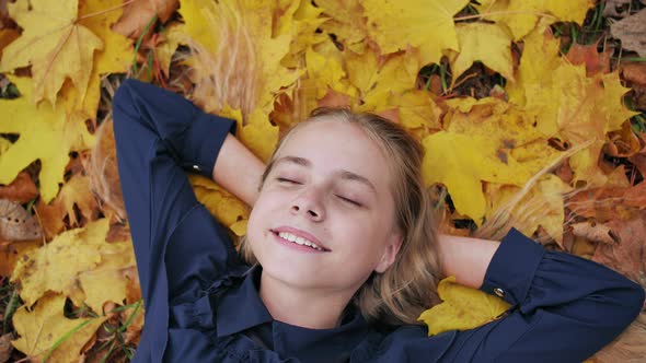 A Young Happy Girl Lies in the Autumn Leaves