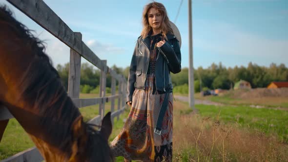 Stylish Female Posing Near Grazing Horse