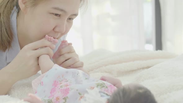 Asian Mother playing with her adorable newborn baby.