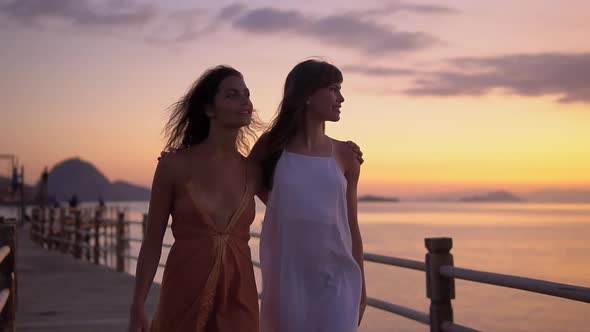 Two Happy Girlfriends Taking a Walk By the Ocean Enjoying Lovely Summer Evening and Each Other