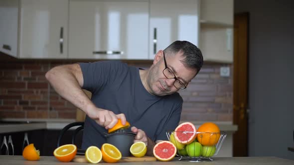 A Man Squeezes Orange Juice with Citrus Juicer