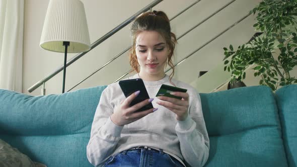 Happy Young Woman Holding Credit Card Using Instant Mobile Payments at Home.