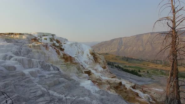 Small cliff near a geyser covered with crystallized calcium carbonate as camera flies by