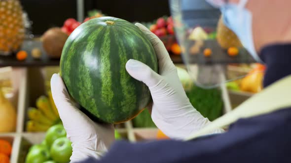 Closeup of a Watermelon in the Hands of a Gloved Vegetable Store Clerk During Quarantine