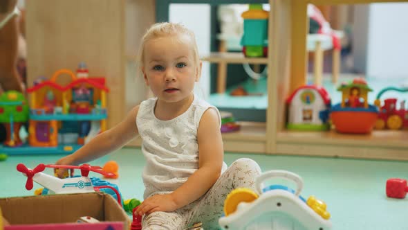 Toddler Girl Playing with Different Plastic Toys Such As Building Blocks Car Toys