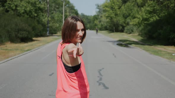 Cute girl invites to run with her in park. Attractive girl invites to follow her to running training