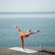 Woman Practices Yoga Near Sea and Keeps Balance - VideoHive Item for Sale
