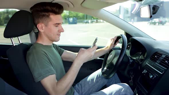 Handsome Young Man Using Cell Phone In A Driver Seat Of The Car.