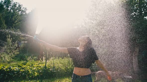 A Beautiful Happy Woman Freshens Up By Pouring Water on Herself From a Hose