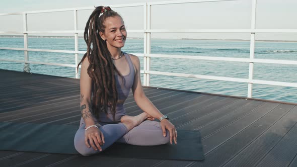 Woman in Lotus Pose Smiling on Pier