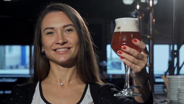 Gorgeous Happy Woman Smiling, Holding Out Her Beer To the Camera 