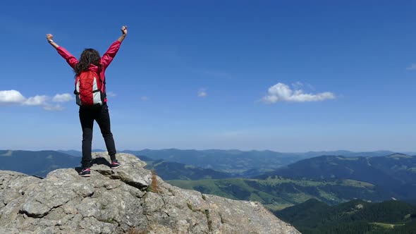 Girl on Top of the Mountain with a Backpack. Rejoice at Achievement