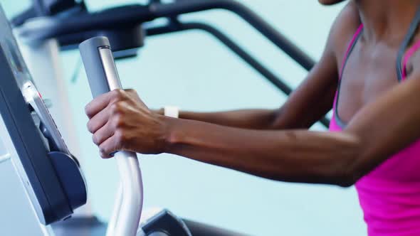 Fit woman exercising on cross trainer