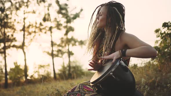 Beautiful Young Hippie Woman with Dreadlocks Playing on Djembe