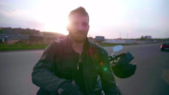 Young Man Sitting on Motorcycle on the Road at Sunset Slow Motion